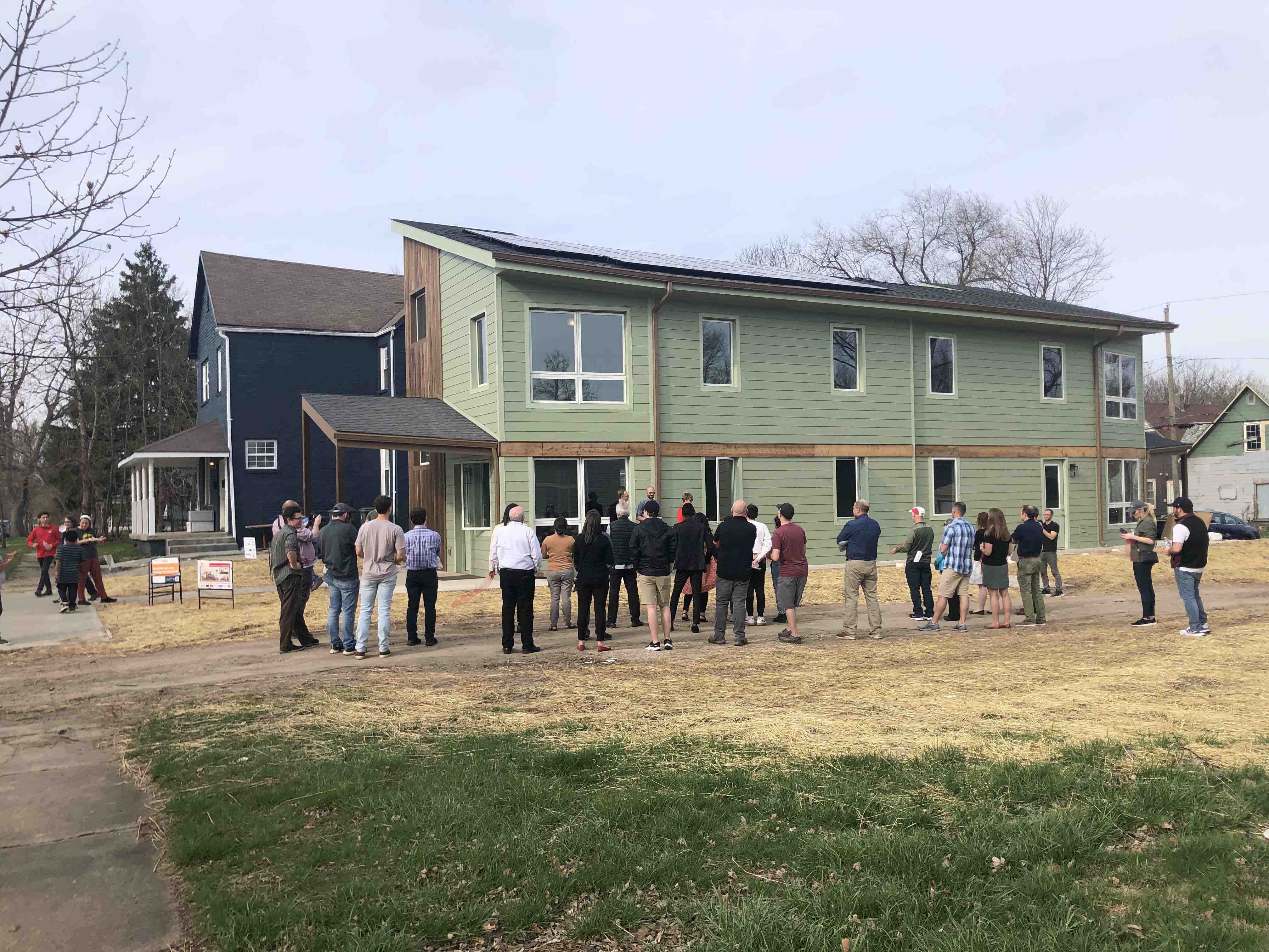 group of people stand outside a student-designed green house called the Alley House